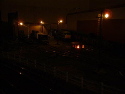 Stoneybridge West Yard by night. Working yard lighting using 'grain of rice' 3V lamps fed with 1.2V DC. Fire in hut 2 x bulbs with 'unstable flip-flop' circuit fire flicker effect.
